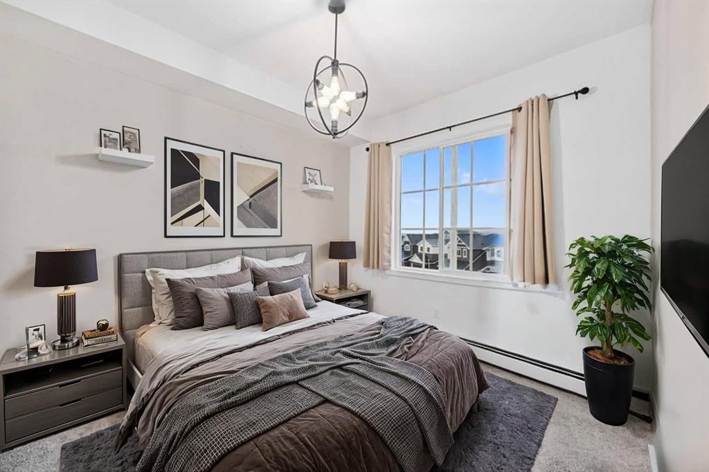Furnished bedroom with large window, neutral decor and modern lighting in Sage Meadows Park condo