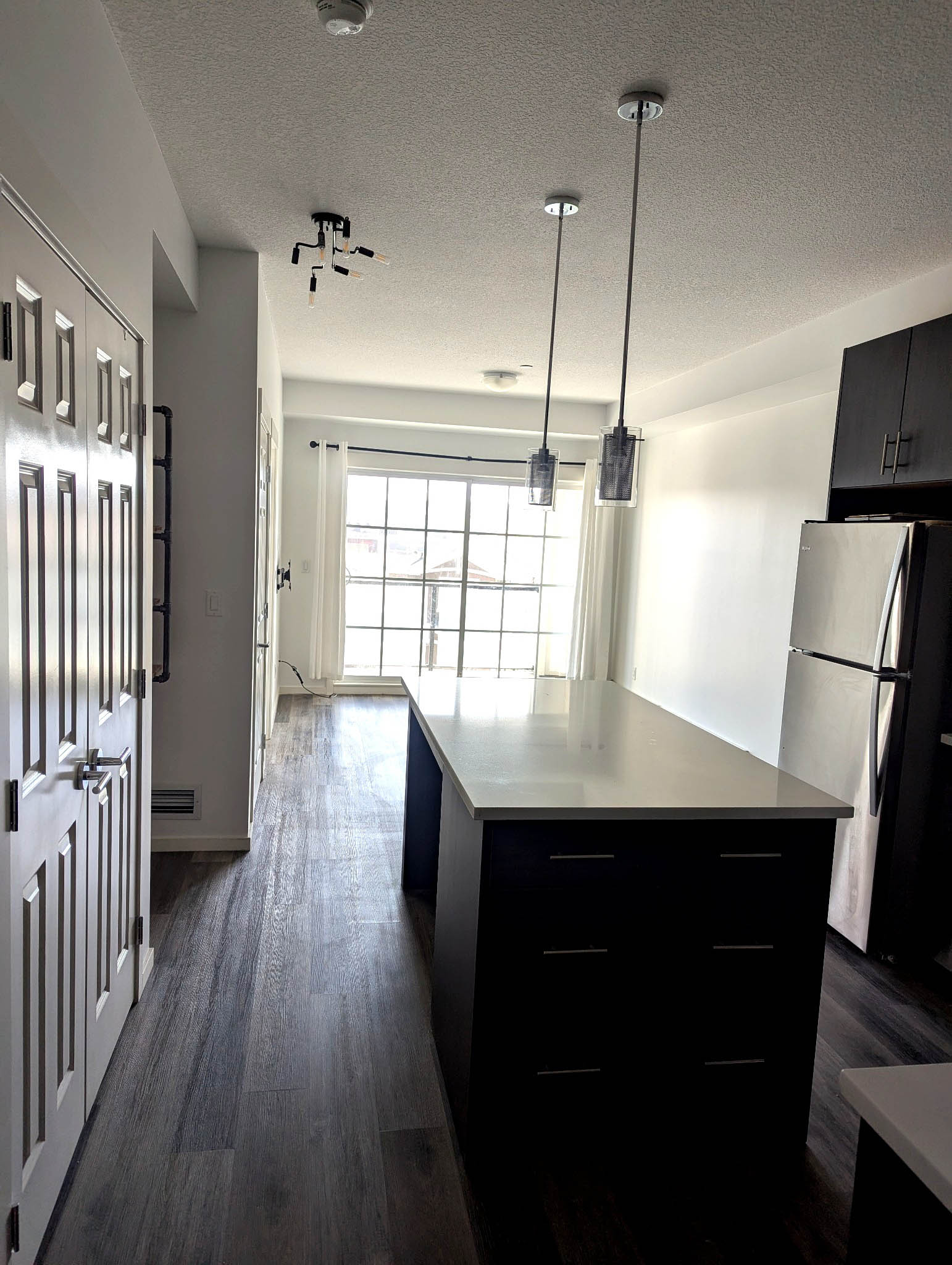 Bright kitchen with island, pendant lights and large windows in Sage Meadows Park condo