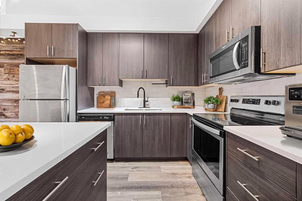 Upgraded modern kitchen with quartz counters, stainless appliances and dark cabinetry