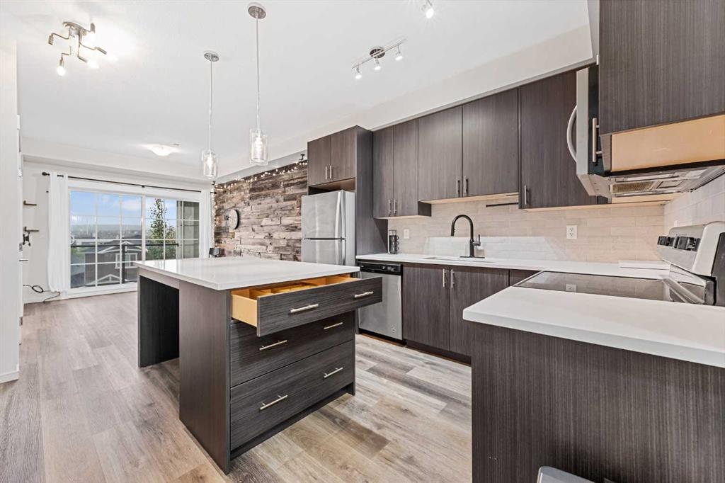 Modern kitchen with island, quartz counters and stainless appliances in Sage Meadows Park condo