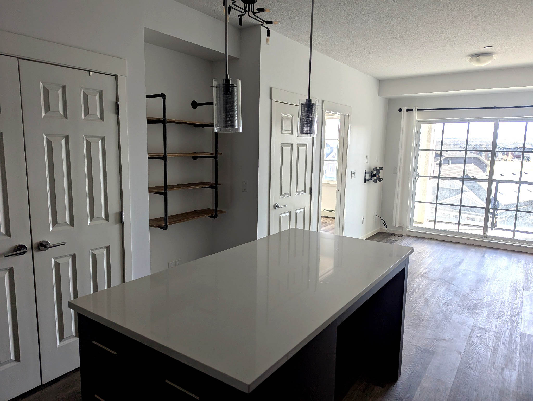 Kitchen island overlooking bright living area with shelving and balcony light