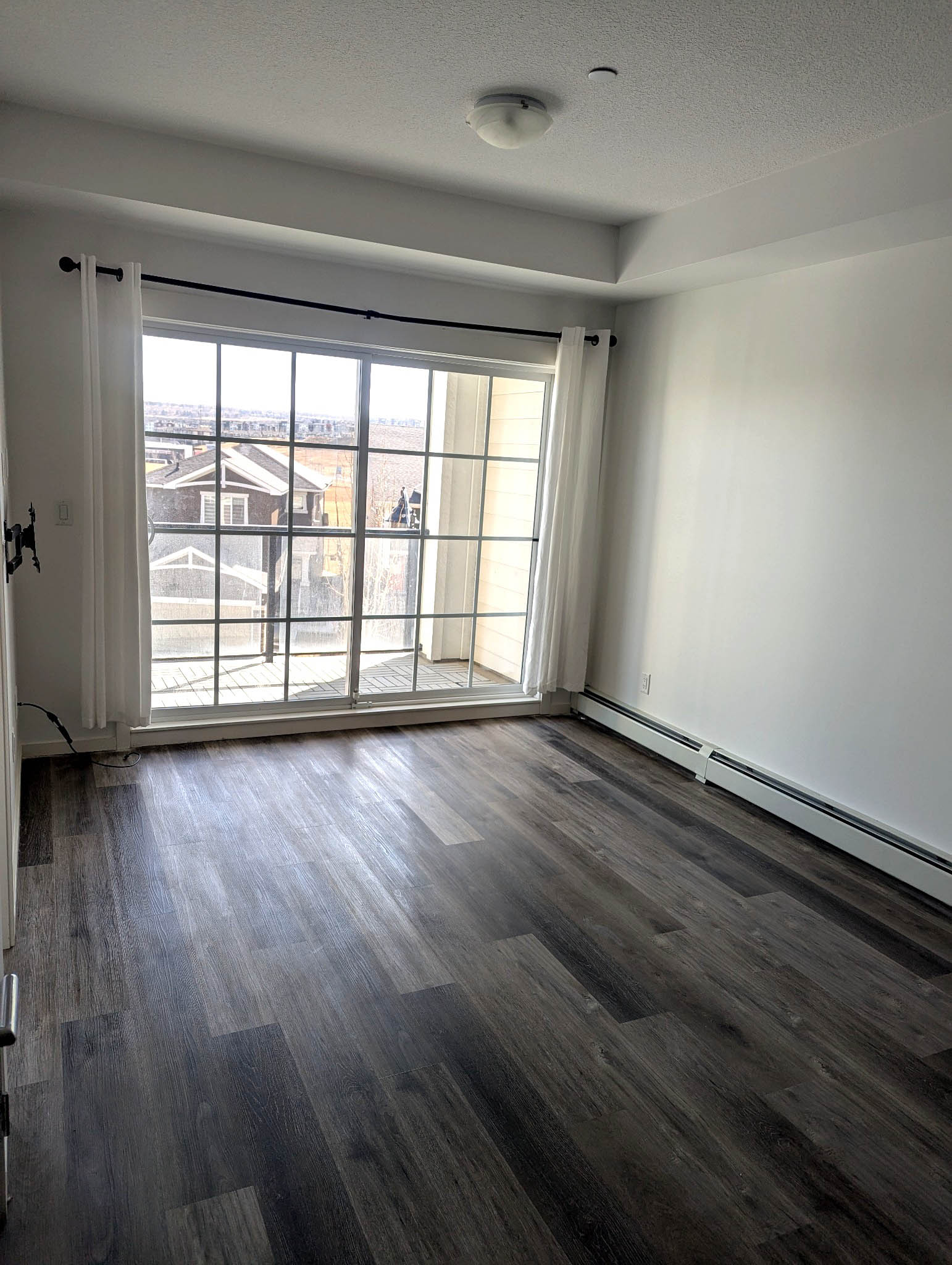 Open living room with wide windows and balcony access in Sage Meadows Park Calgary condo